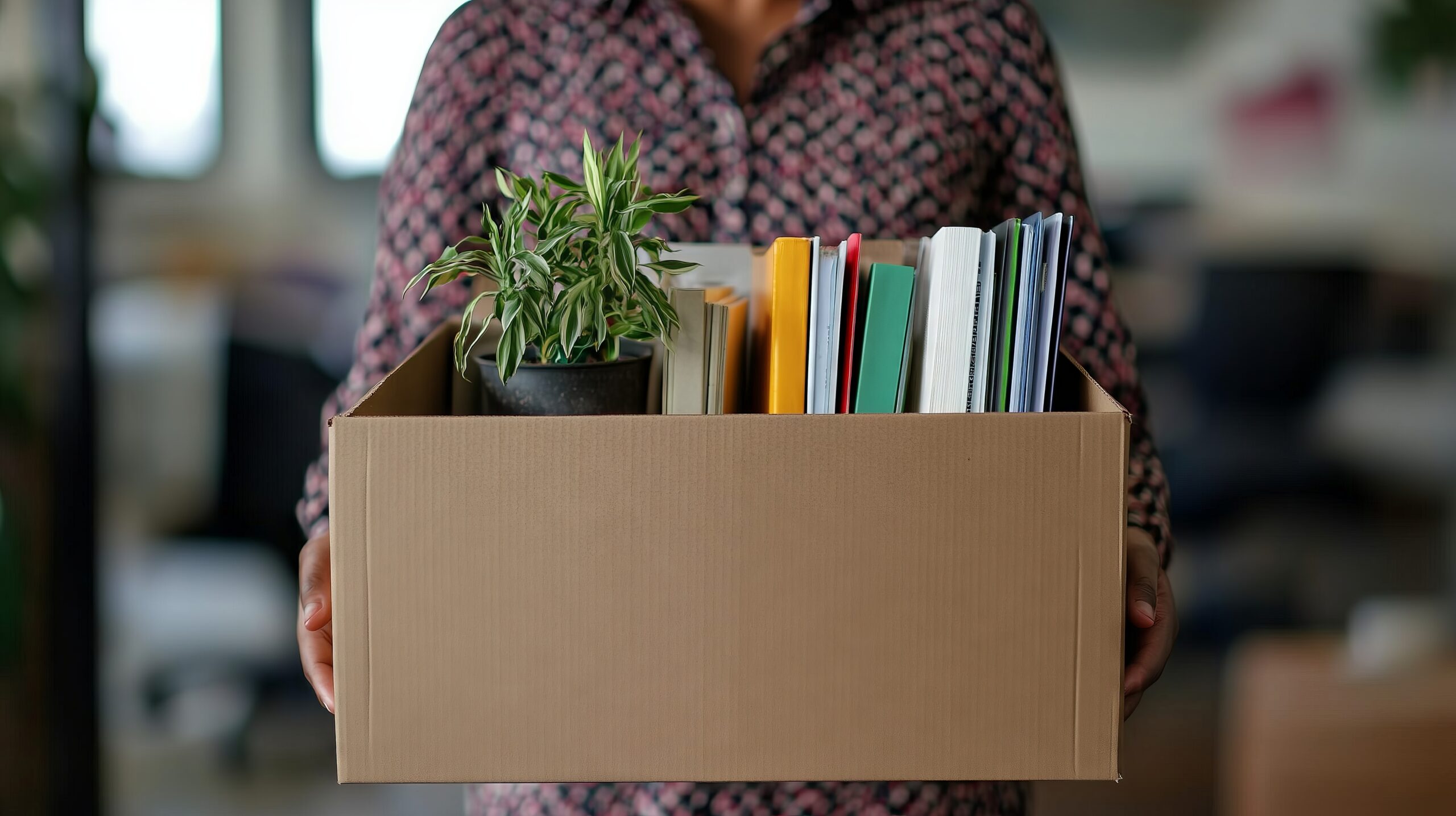 Office worker carrying cardboard box with belongings, resignation, layoff, or new opportunity